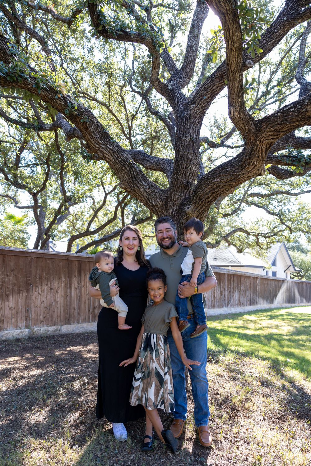 Family portrait beneath spreading branches of a majestic oak tree.