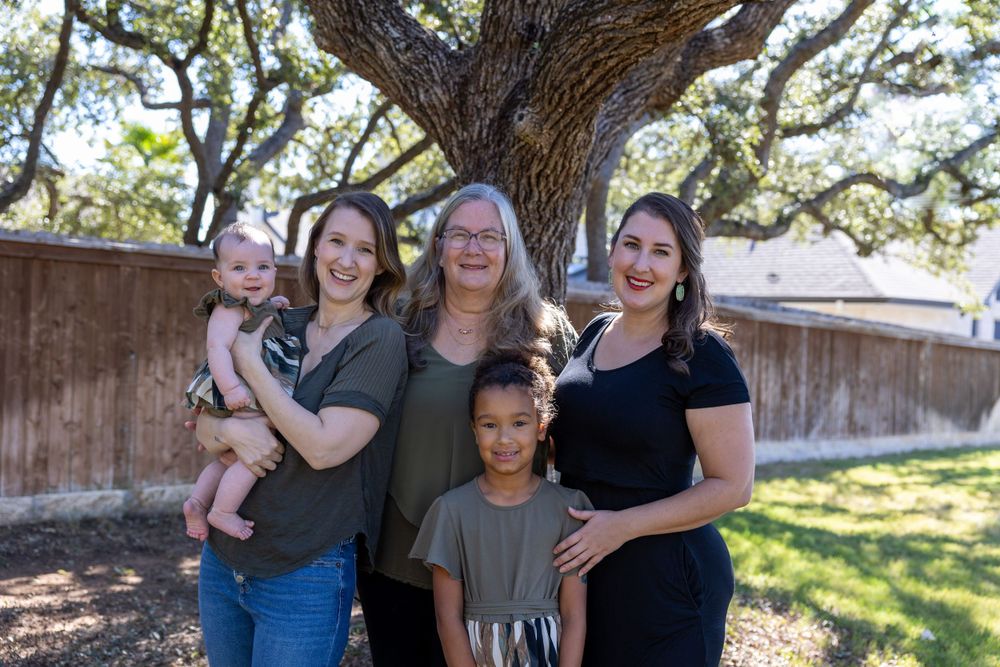 Family group gathered under a large oak tree on a sunny afternoon.