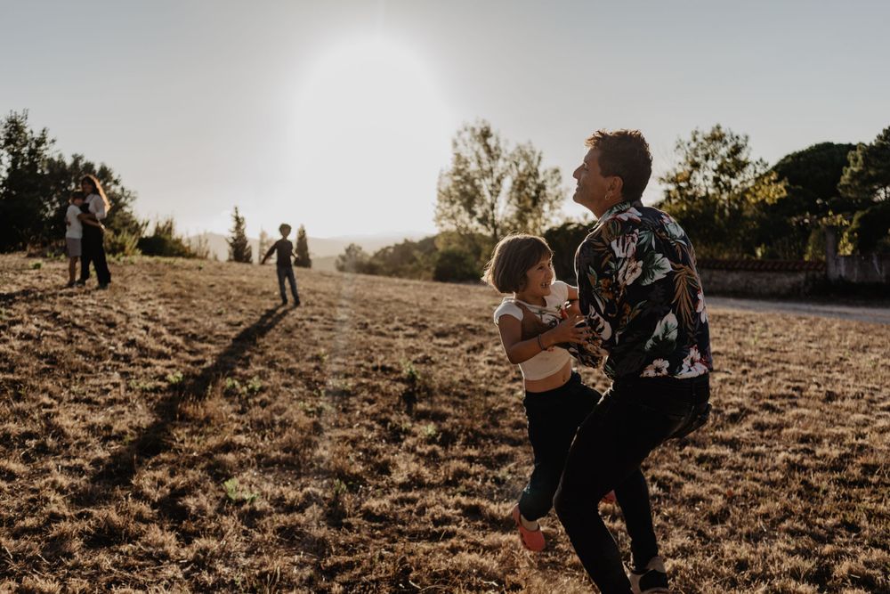 Sessão de família ao ar livre na natureza. Fotografia lifestyle espontânea que capta alegria, movimento e ligação autêntica ao pôr do sol.