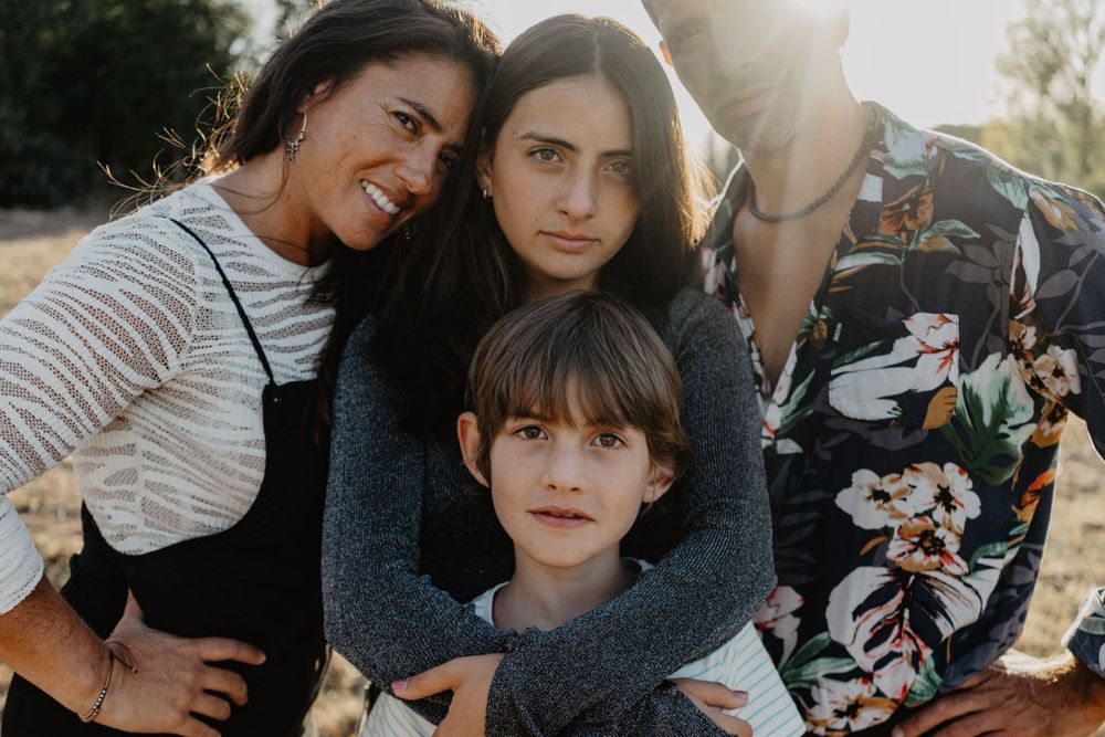 Sessão de família ao ar livre na natureza. Fotografia lifestyle espontânea que capta alegria, movimento e ligação autêntica ao pôr do sol.