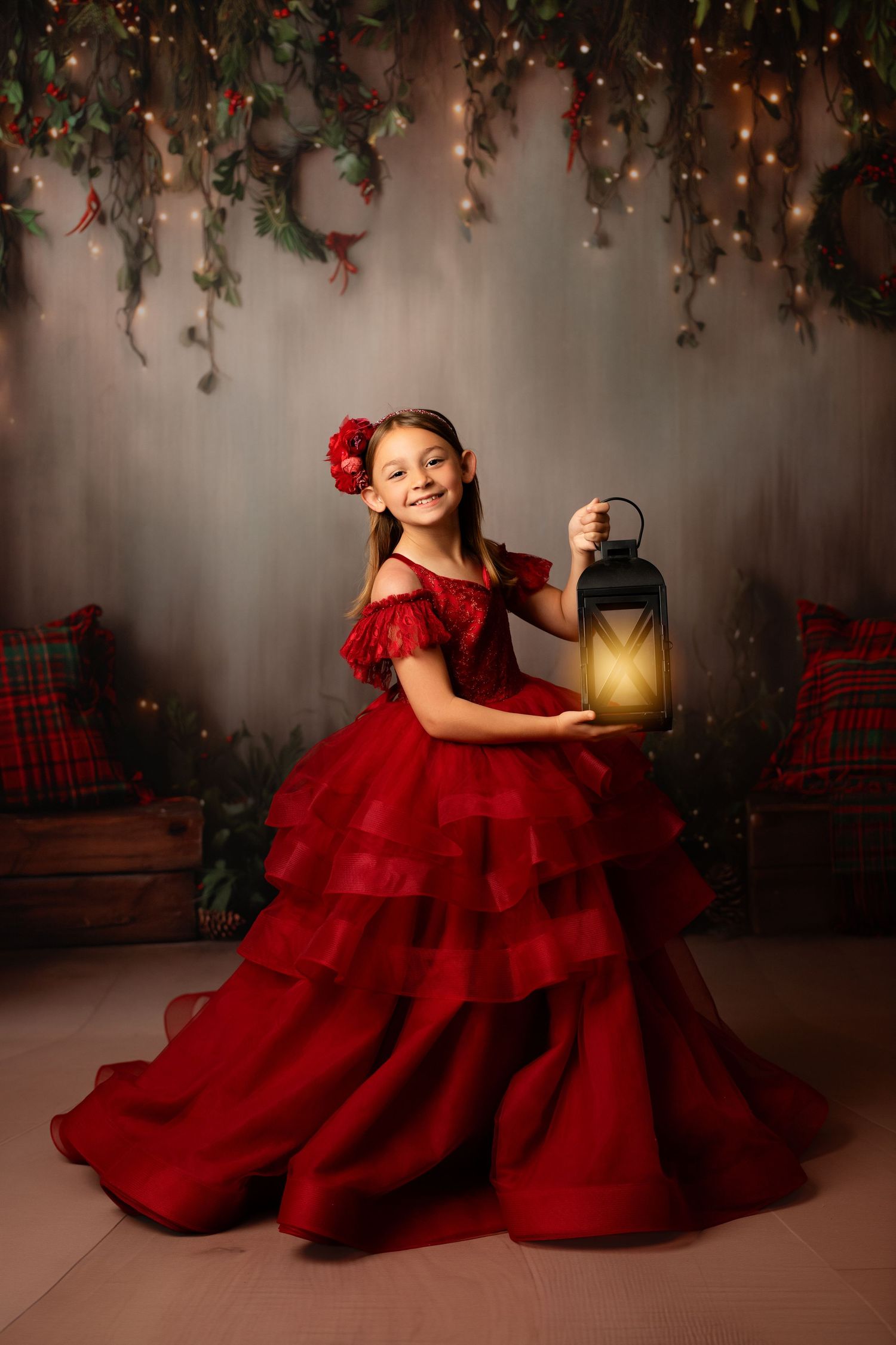 Festive Christmas portrait with red ball gown against decorated doorway with lit trees.
