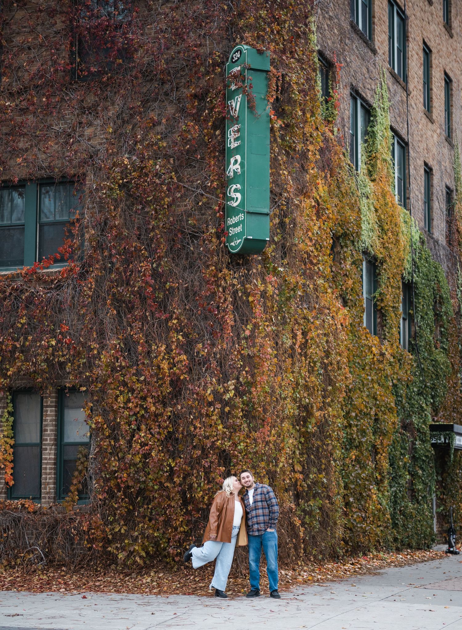 A sequence of four photos showing people walking past a brick building with autumn foliage and green traffic lights.