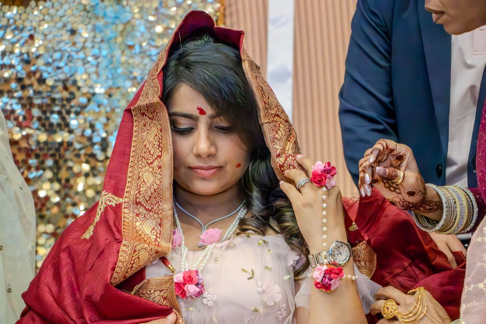 Traditional bride in red and gold attire adjusting jewelry during ceremony.