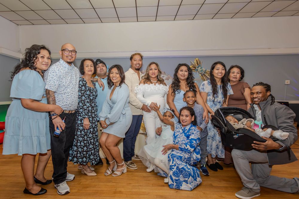 Group photo of family and friends gathered at a celebration event in a community hall.