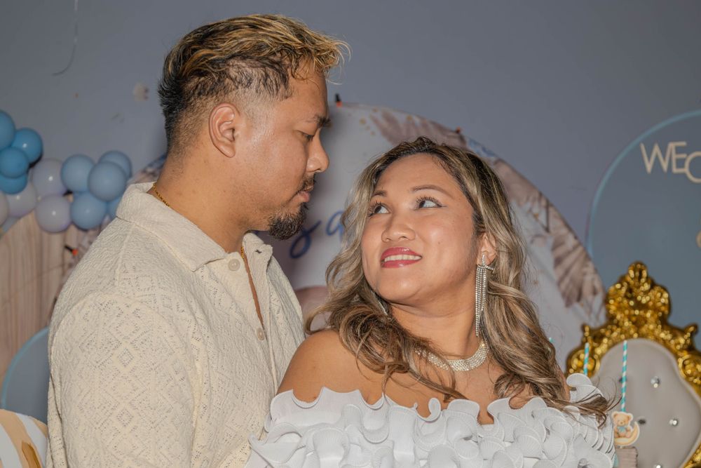 Romantic moment captured at a celebration with balloon decorations and golden throne backdrop.