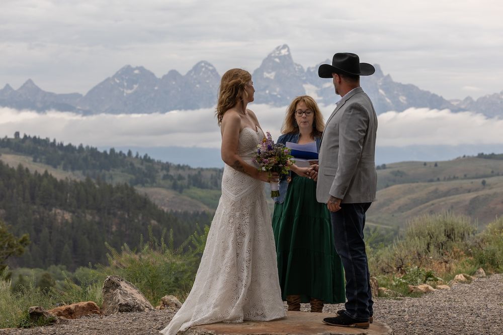 Outdoor wedding ceremony with couple and officiant against Grand Teton mountain backdrop in Wyoming.