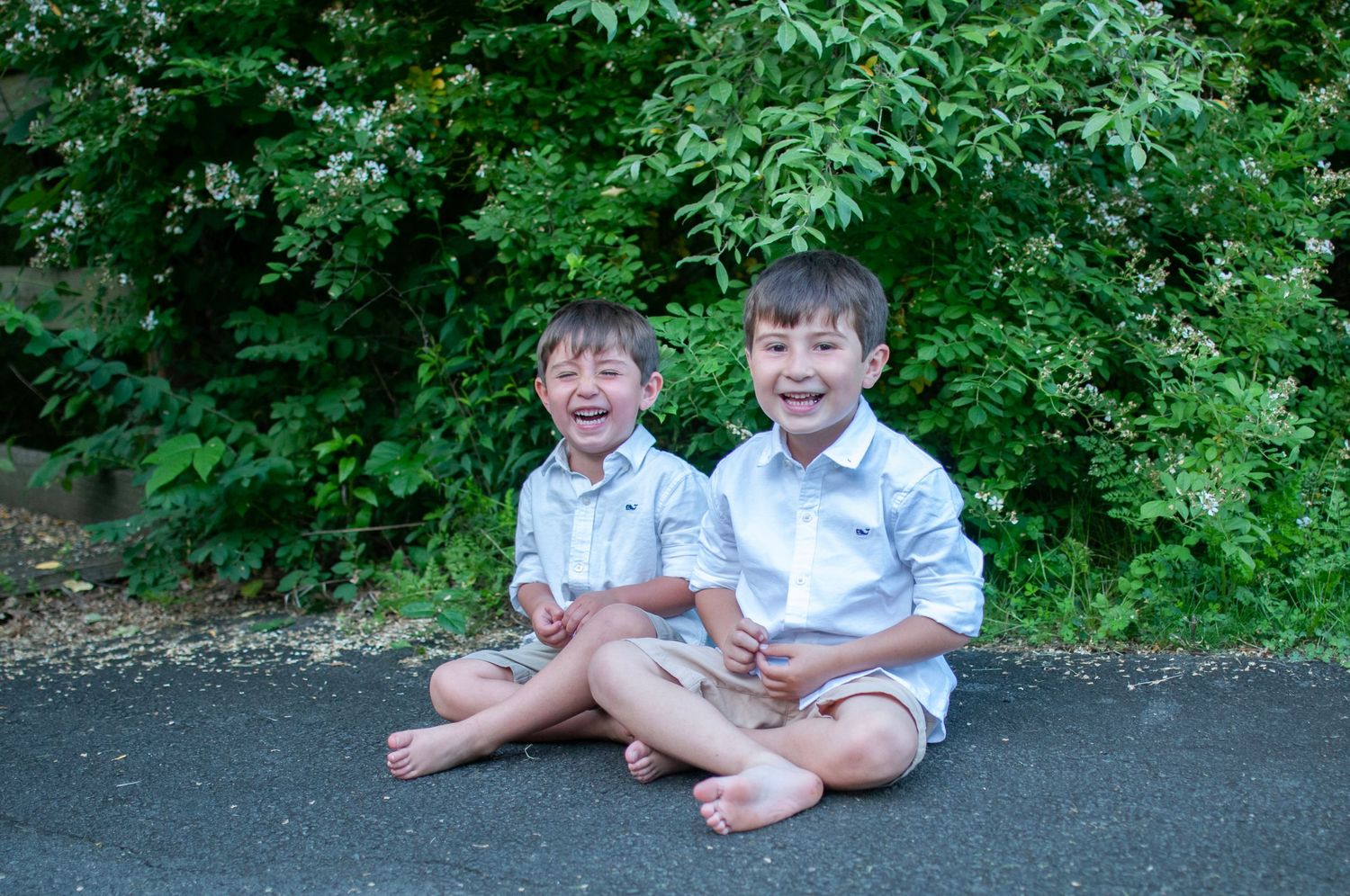 Two young brothers sitting together laughing outside photo
