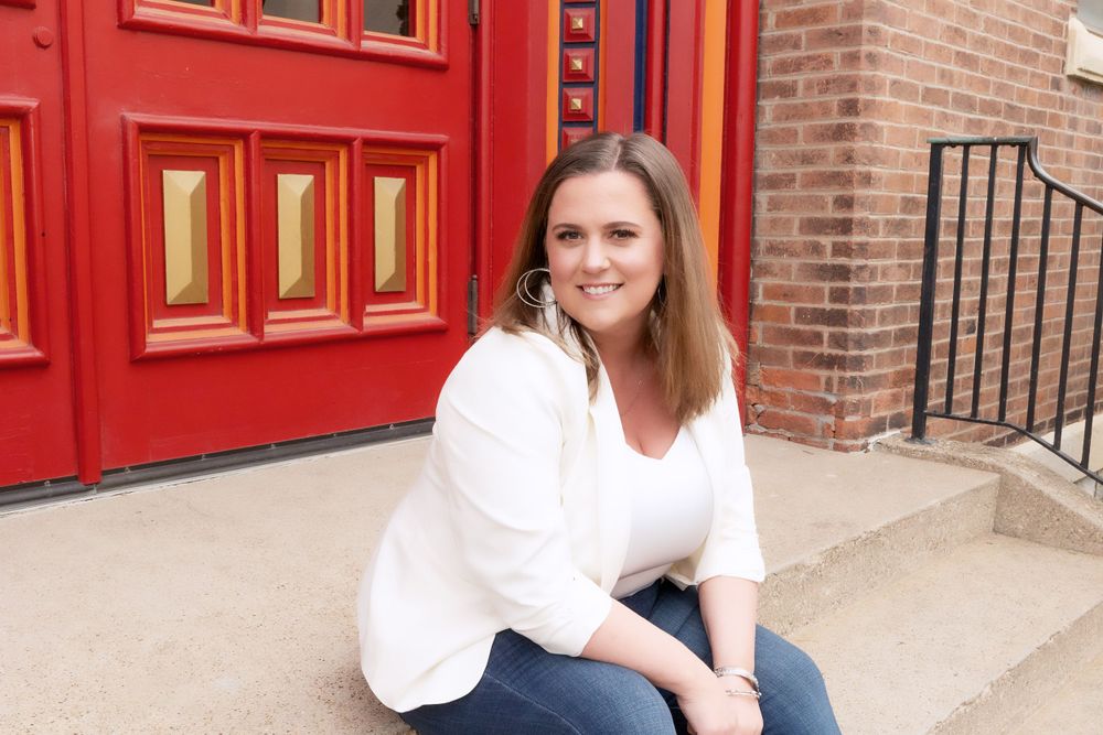Casual portrait by historic red doors on brick building steps.