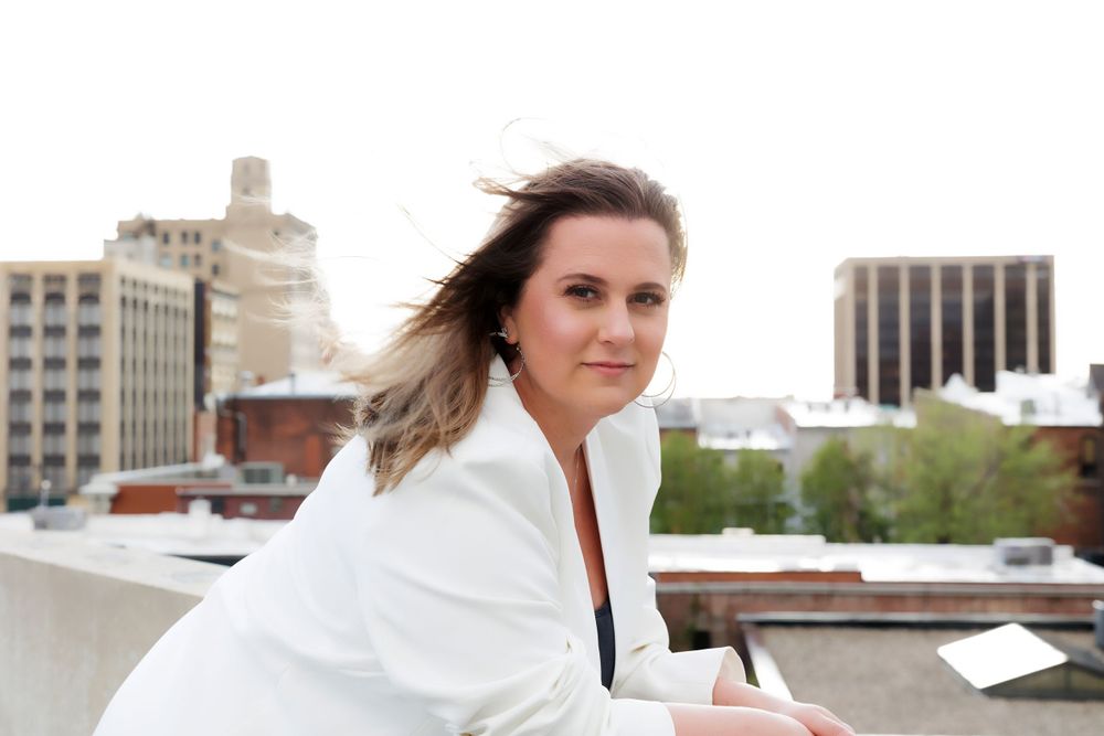 Professional portrait on urban rooftop wearing white blazer.