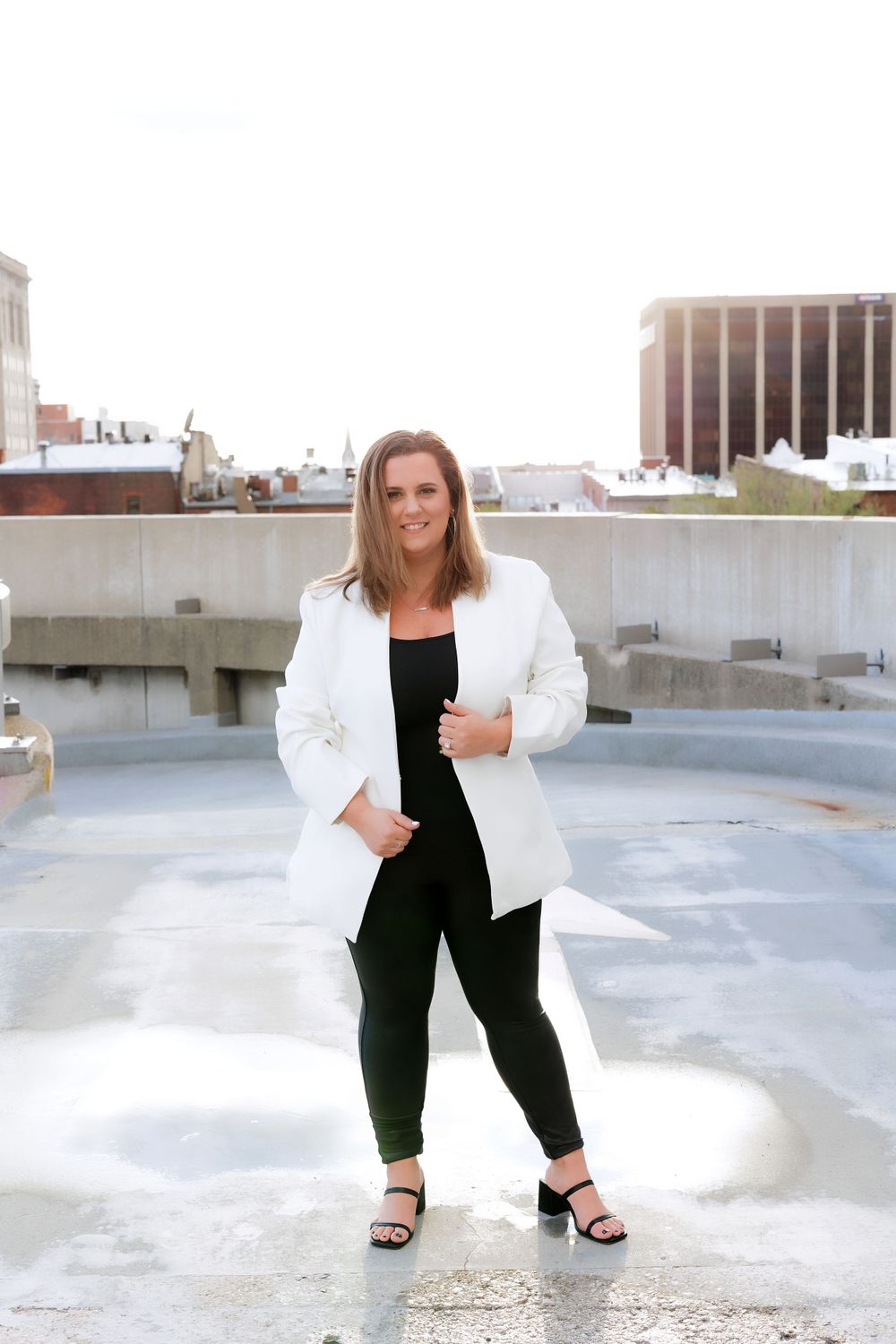Full body fashion shot on rooftop wearing white blazer and black outfit.