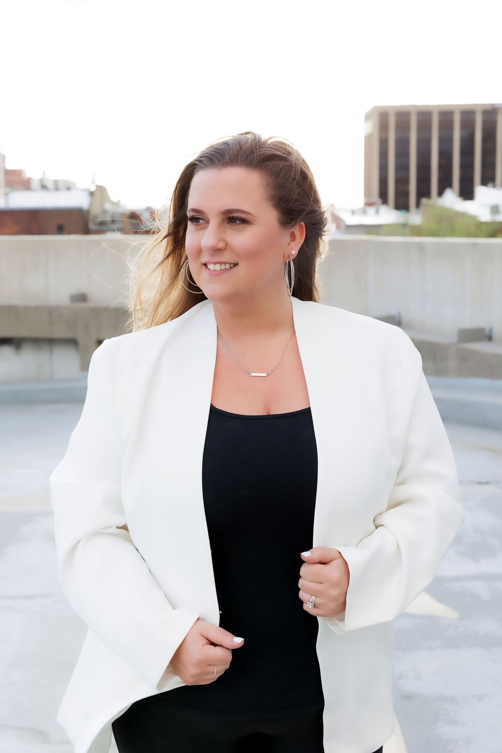 Professional attire featuring white blazer and black top captured in outdoor rooftop photoshoot.