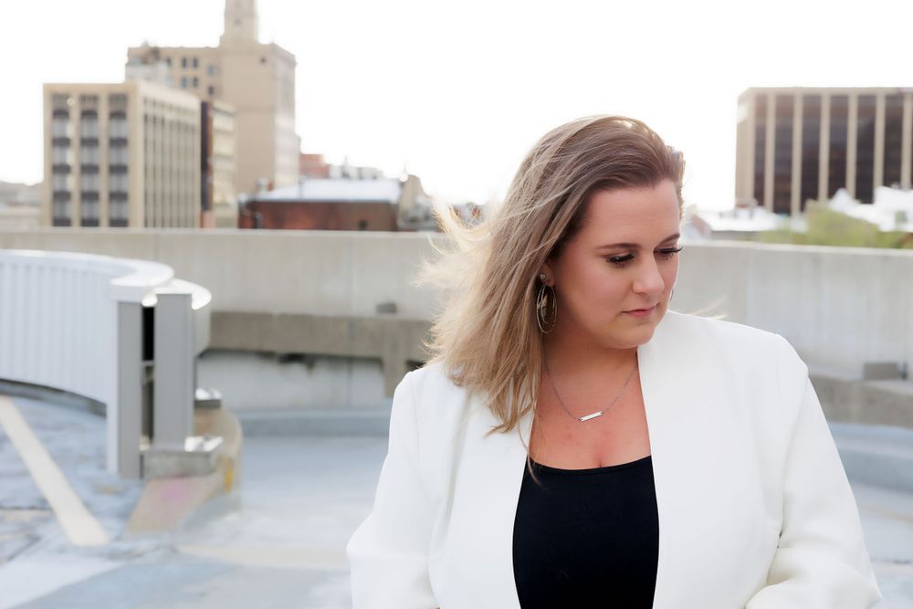 Contemporary business fashion showcased on city rooftop with industrial architecture in background.