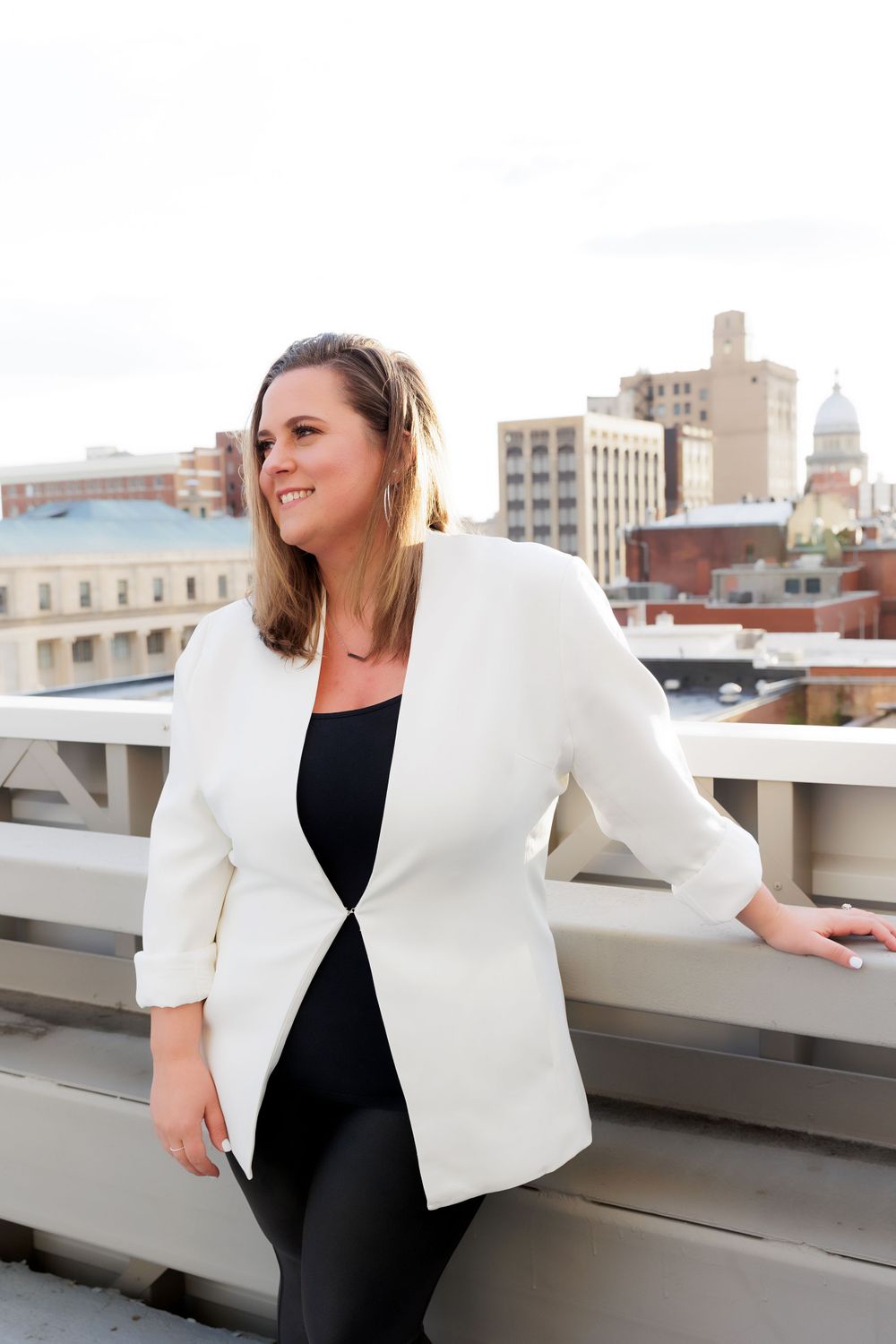Sophisticated business look with white blazer styled against downtown cityscape backdrop.