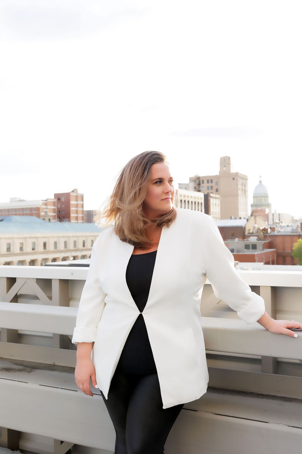 Modern professional wear featuring crisp white blazer photographed against urban rooftop setting.