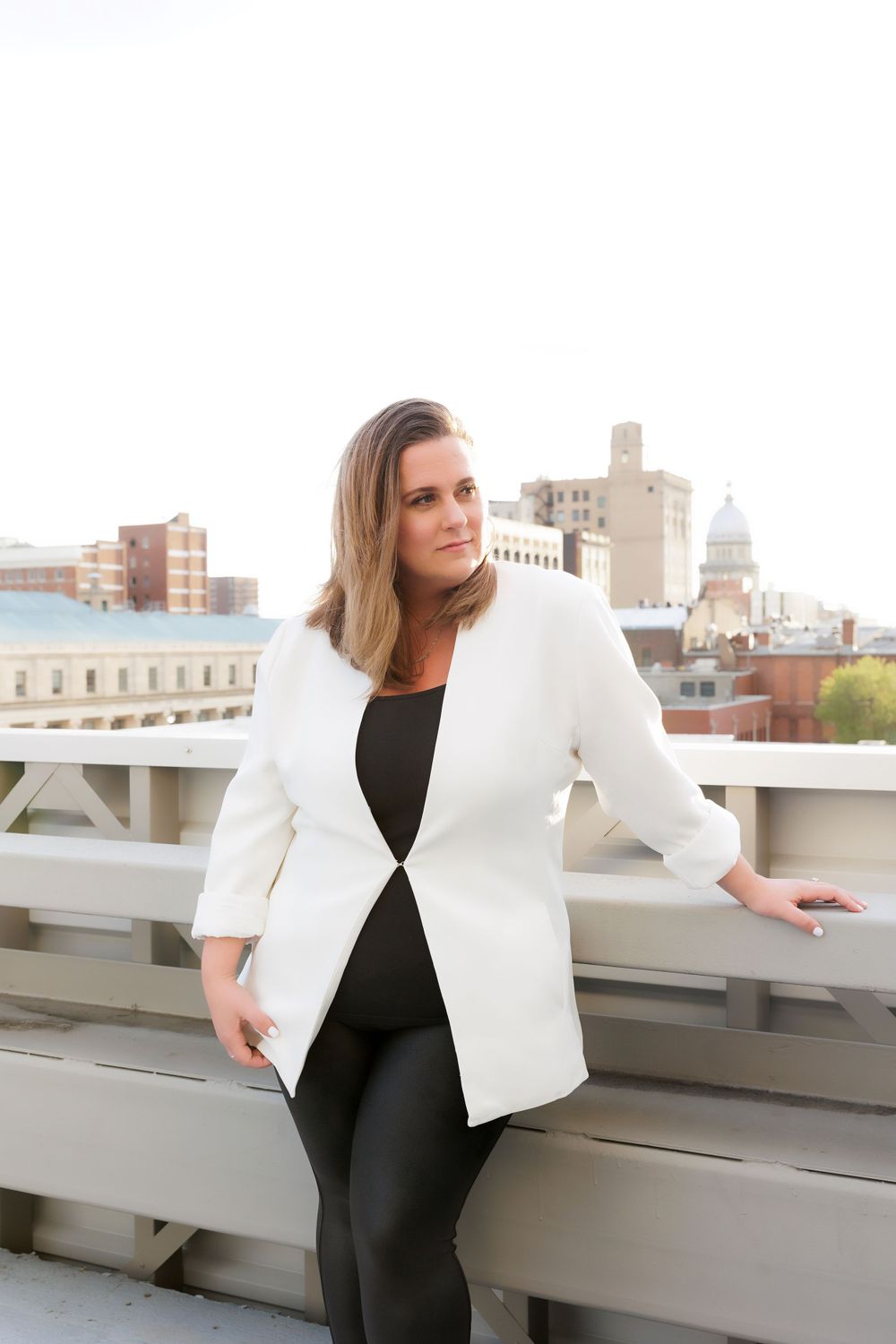 Elegant white blazer and black ensemble styled against urban skyline backdrop on rooftop terrace.