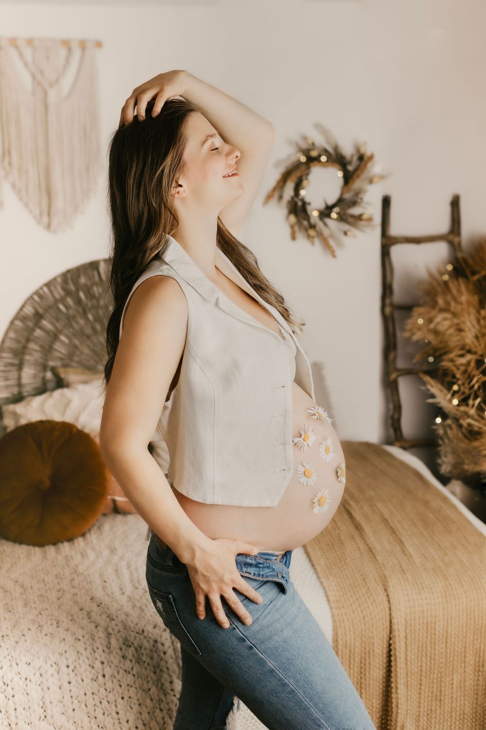 Casual maternity portrait with denim and white top in boho-inspired setting.