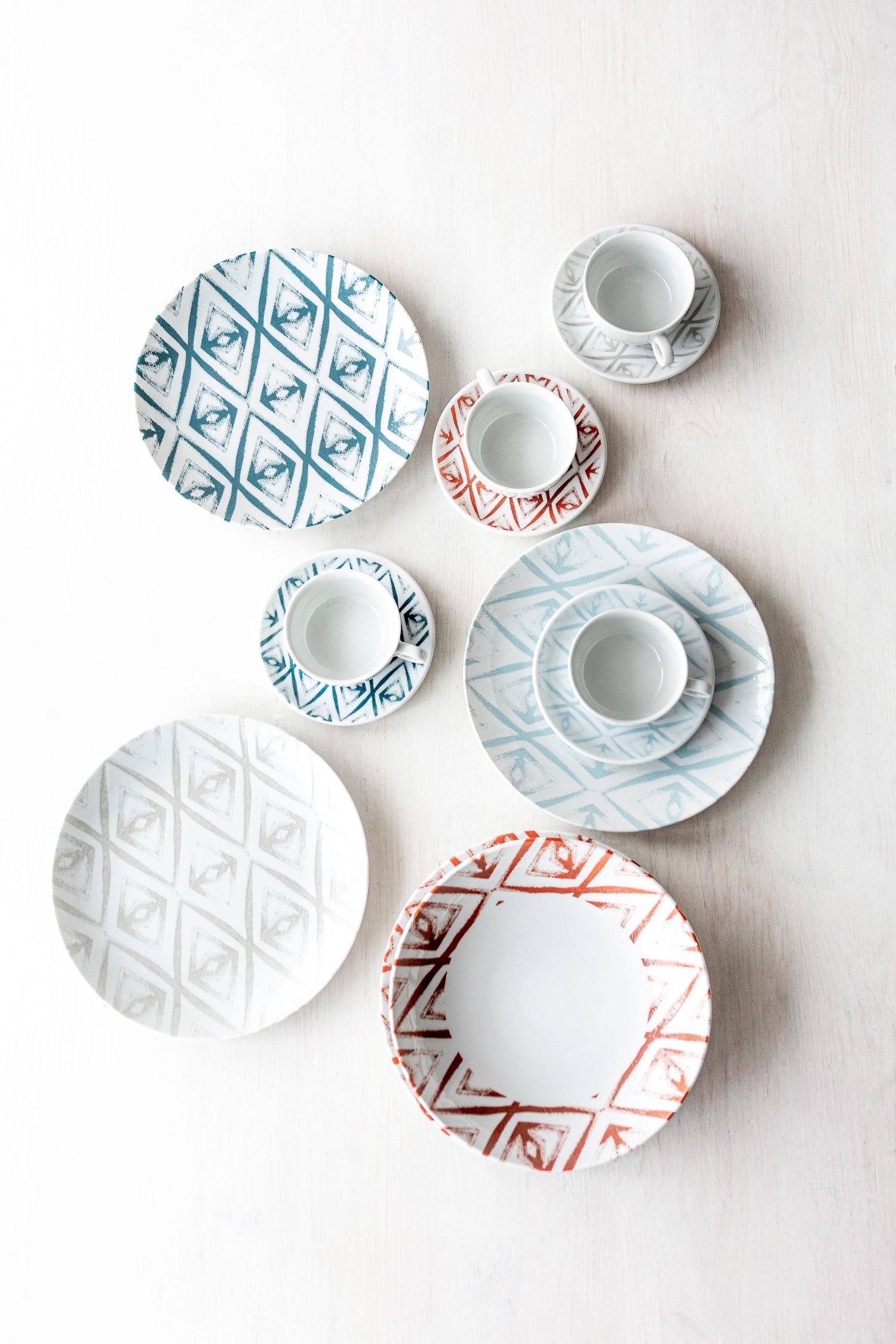 Digitally printed porcelain plates and cups with diamond patterns in blue, red, and grey.