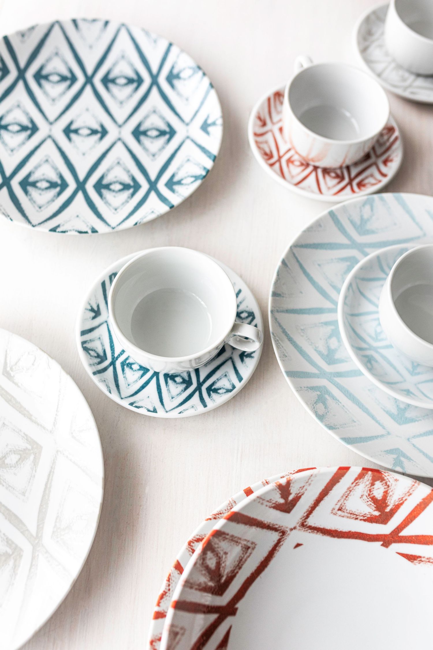 Digitally printed porcelain plates and cups with diamond patterns in blue, red, and grey.