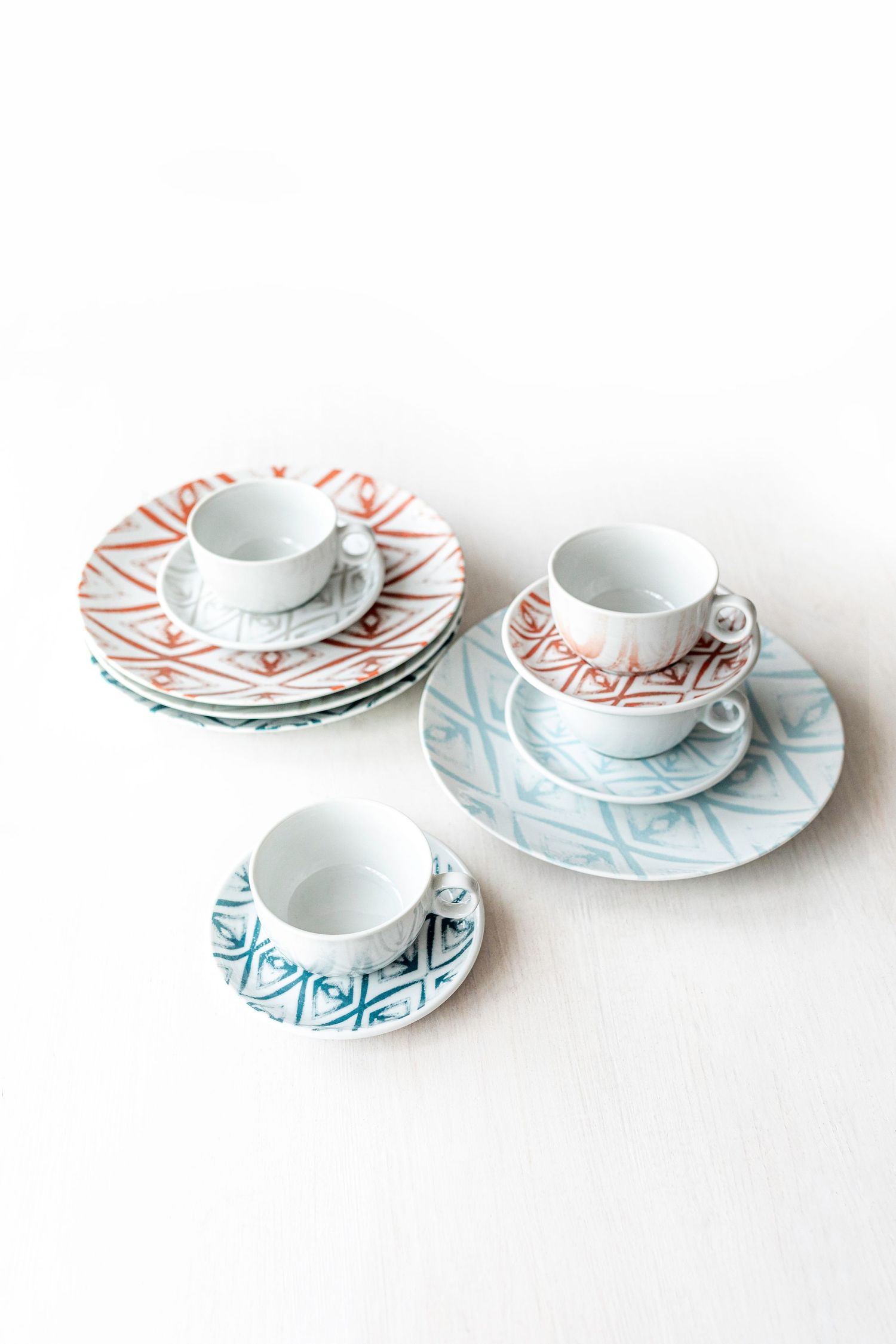 Digitally printed porcelain plates and cups with diamond patterns in blue, red, and grey.