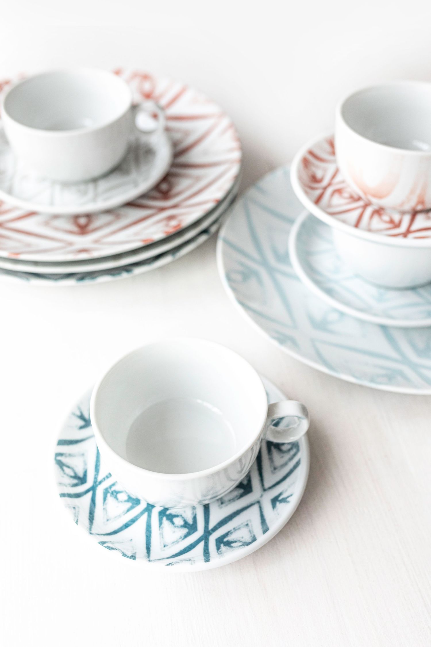 Digitally printed porcelain plates and cups with diamond patterns in blue, red, and grey.