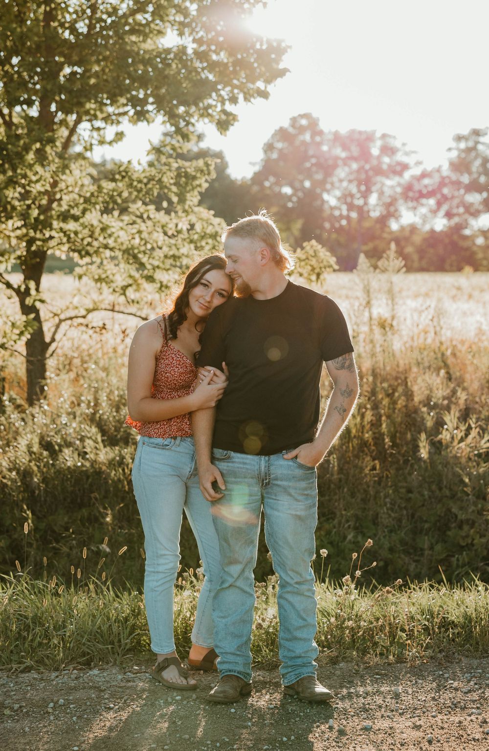 A couple sharing an intimate moment in a golden sunlit field at sunset.