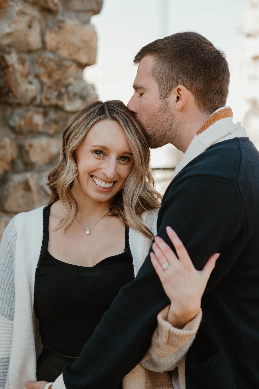 A romantic outdoor portrait against a stone wall background.