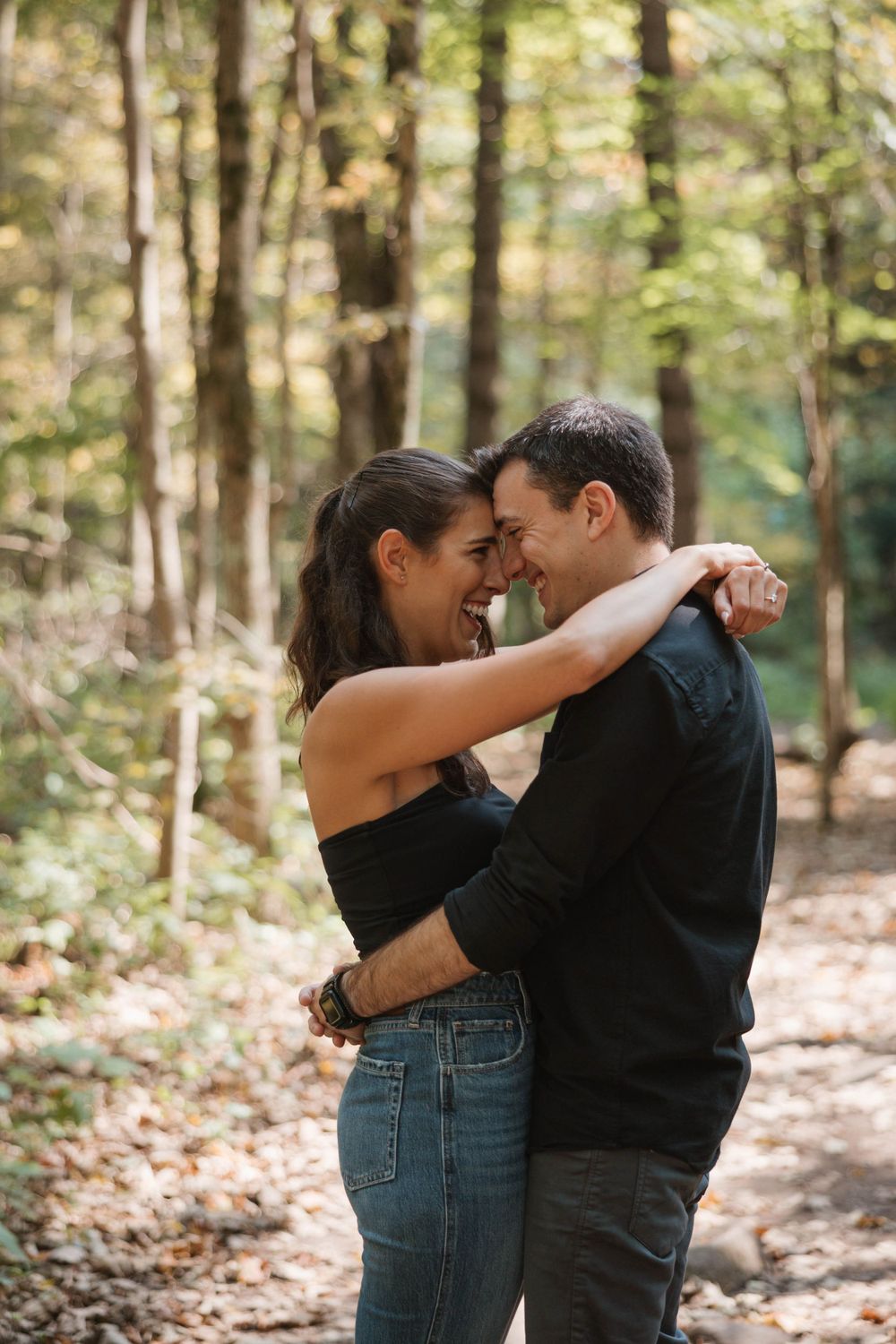 A tender embrace shared between a couple on a sunlit forest path.