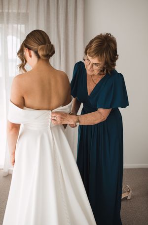 Series showing dress preparation with someone in navy blue helping adjust a white wedding gown.