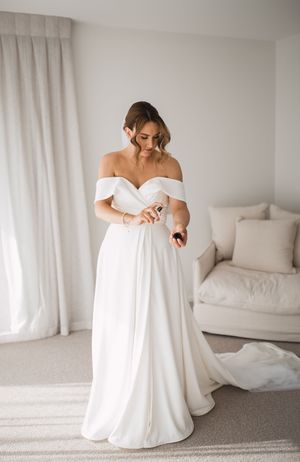 Sequence of bride in white off-shoulder wedding dress sitting on floor in bright room.