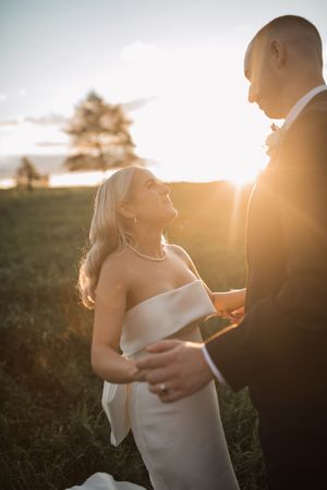 Couple shares intimate moment in sunlit field during golden hour wedding photoshoot.