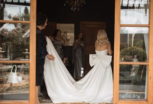 Wedding dress train flowing gracefully through window-lined corridor.