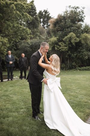A romantic wedding couple embraces and dips on a grassy lawn during their outdoor photo session.