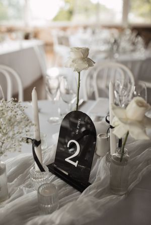 Elegant white wedding reception table setting with floral centerpieces and table numbers.
