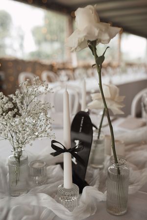 Minimalist wedding centerpieces with white flowers in glass vases on reception tables.