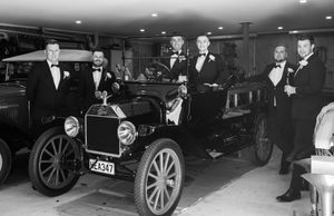 A vintage black and white photograph showing classic cars in a museum or showroom setting.