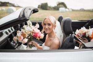Elegant wedding car decorated with pink and white floral arrangements.