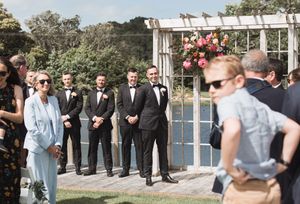 Wedding party members gather outdoors for photos near white French doors.
