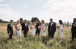 Wedding party walking through tall grass in an outdoor field setting.