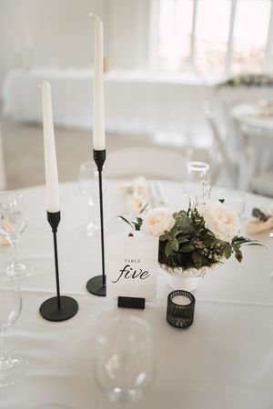 Elegant white wedding reception table with black candlesticks and delicate floral arrangements.