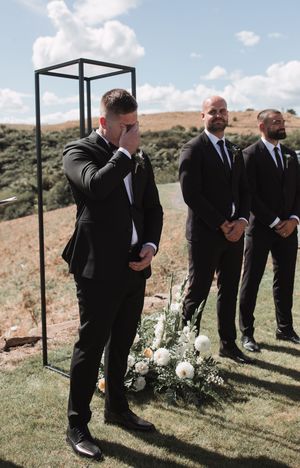 Emotional wedding ceremony moment at outdoor venue with black metal arch and desert landscape backdrop.