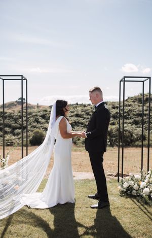Intimate outdoor wedding ceremony with couple exchanging vows between black metal arches.