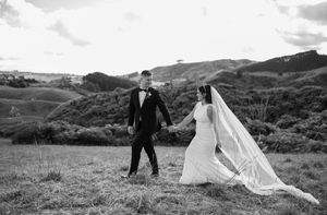 A couple dances together on a grassy hilltop with dramatic cloudy skies in the background.