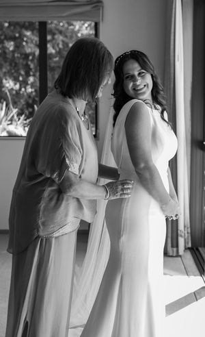 Women in white dresses gather indoors near windows in black and white photography.