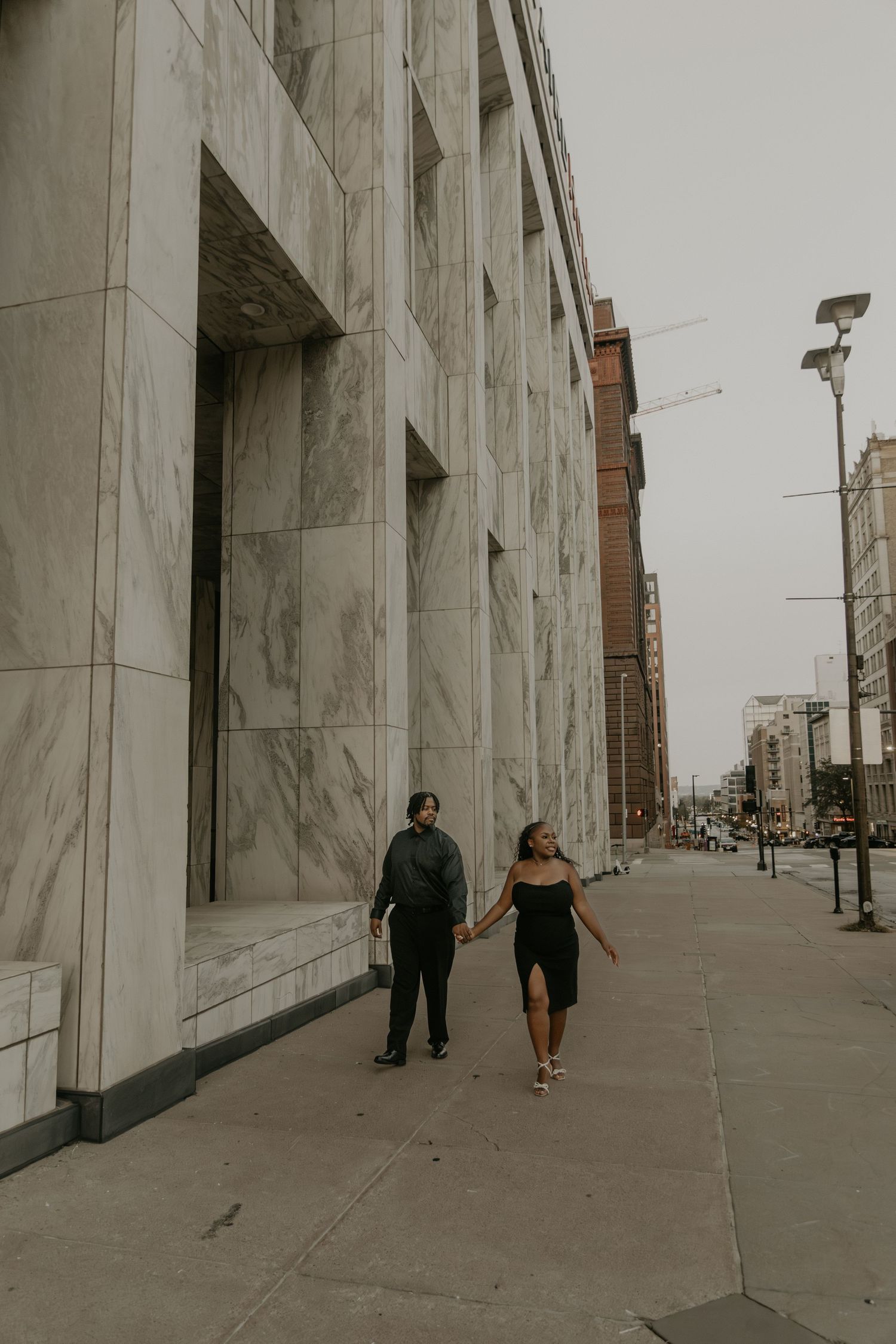 Couple sharing intimate moment on rooftop with urban cityscape background in muted tones.