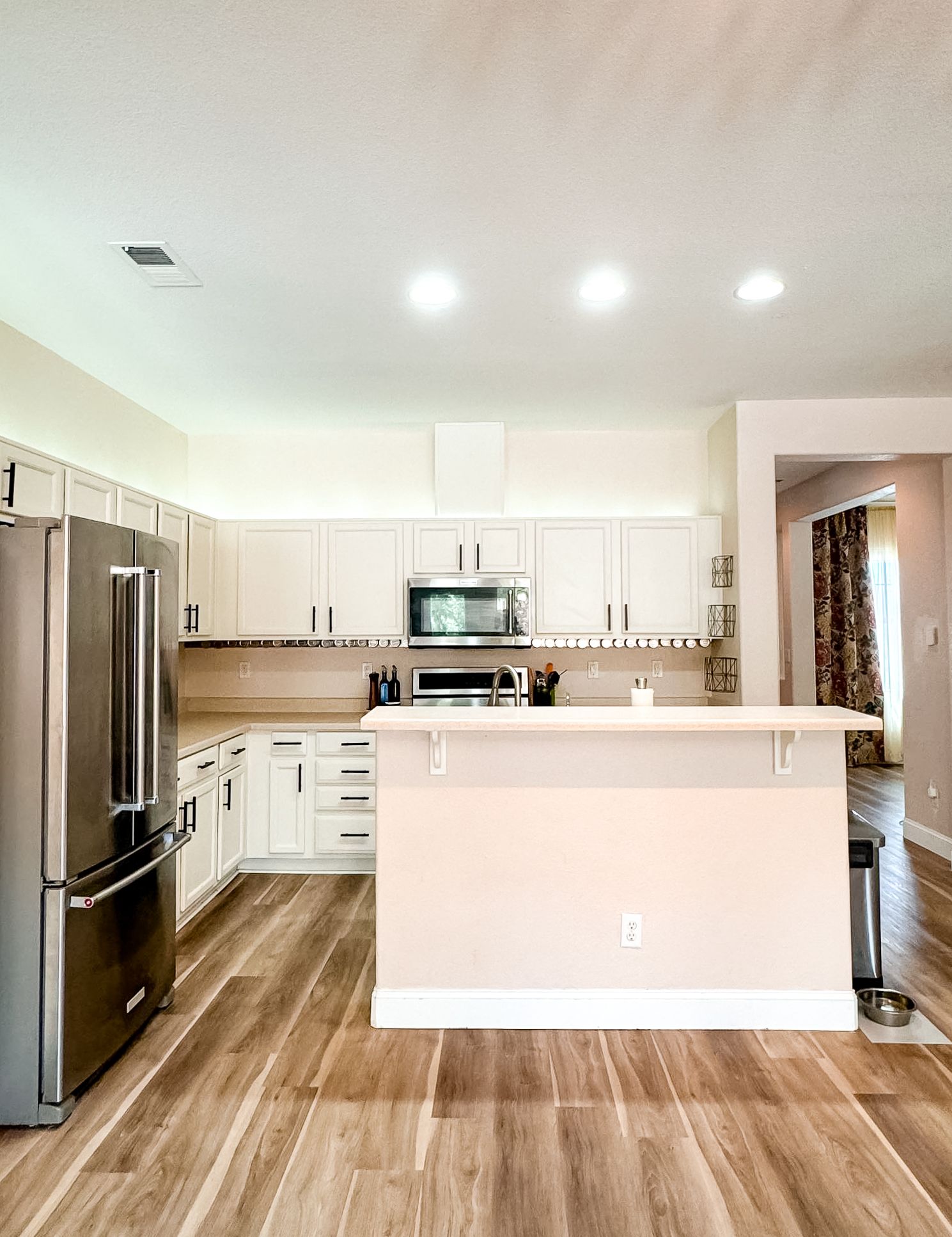 Modern white kitchen with stainless steel appliances and hardwood floors.