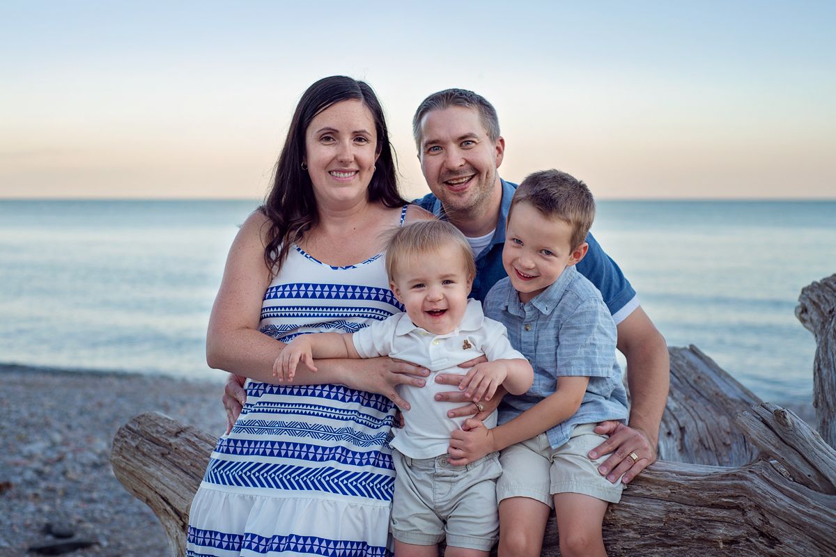 family of 4 in coordinated outfits at Bowmanville beach for a family photography session.
