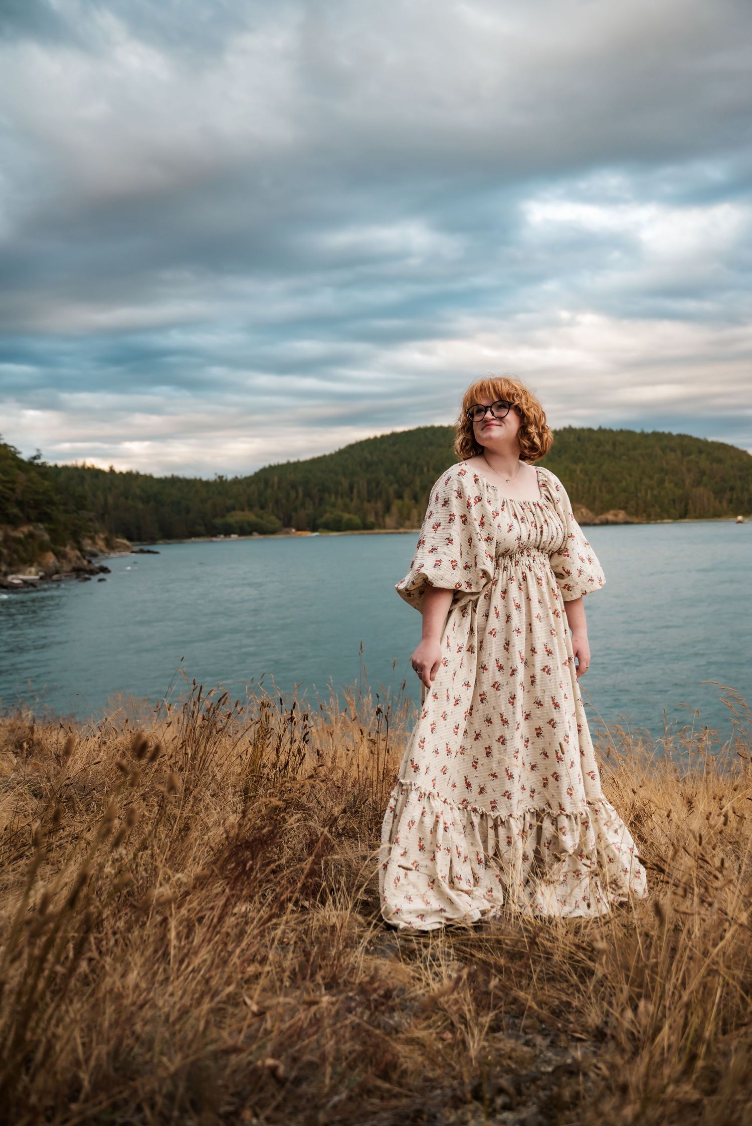 senior girl plays with dress backed by dramatic skies over deception pass state park