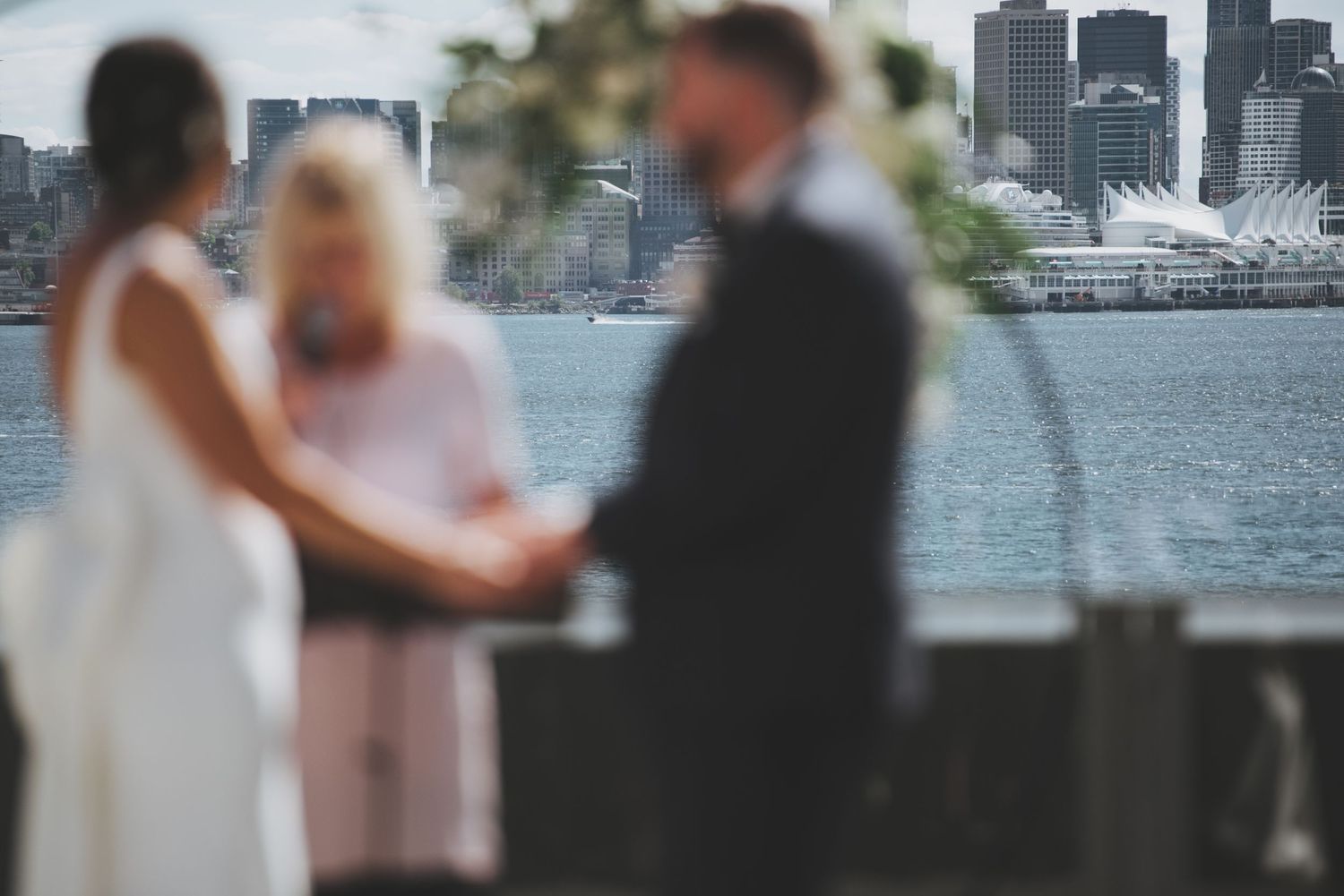Waterfront wedding ceremony with city skyline creating dramatic backdrop.