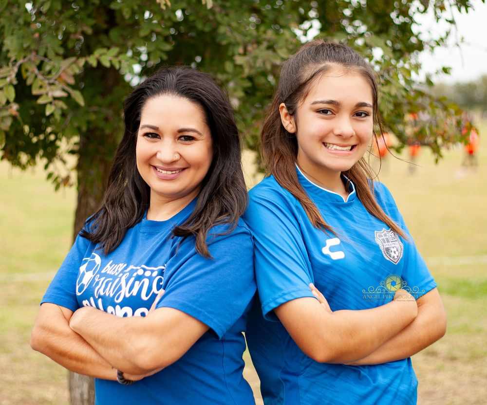 Two teammates in bright blue uniforms pose together outdoors.