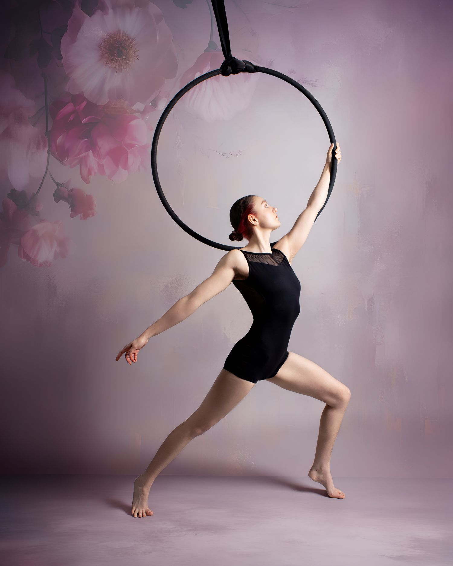 Aerial performer executing a graceful pose on blue silk against dark background with dramatic lighting.